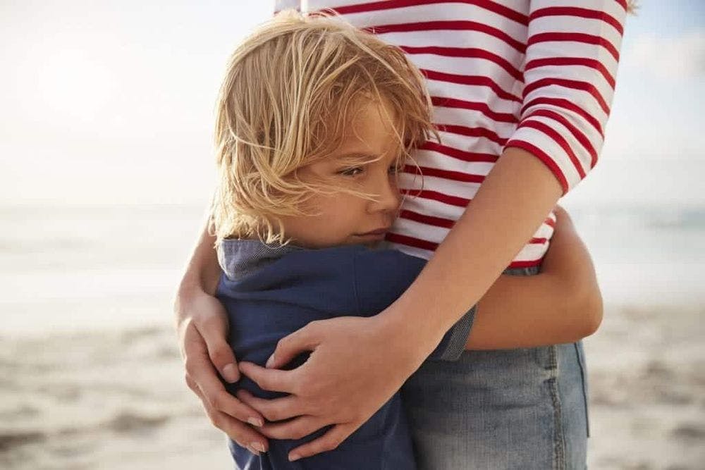 Close Up Of Mother Hugging Son On Summer Beach Vacation