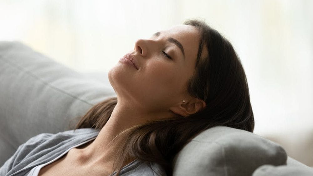 young woman deep breathing at home for health benefits 