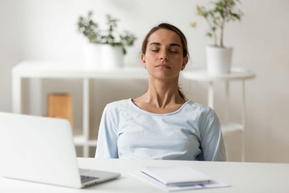 calm woman deep breathing meditating at work