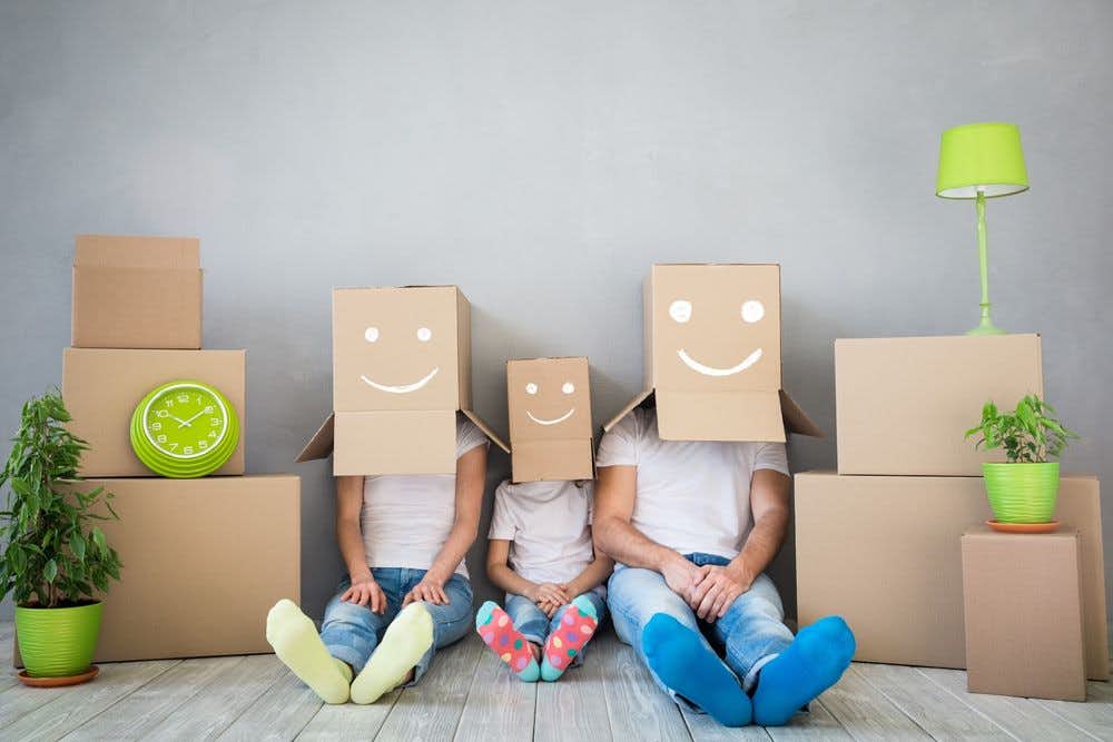 A family with moving boxes painted with smiley faces on their heads