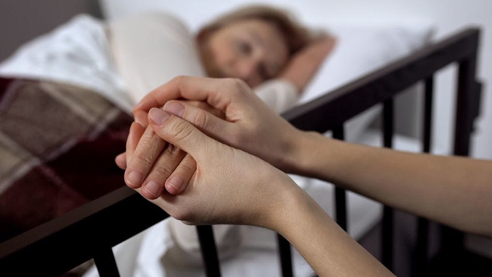 Holding the hands of a patient in a sick bed