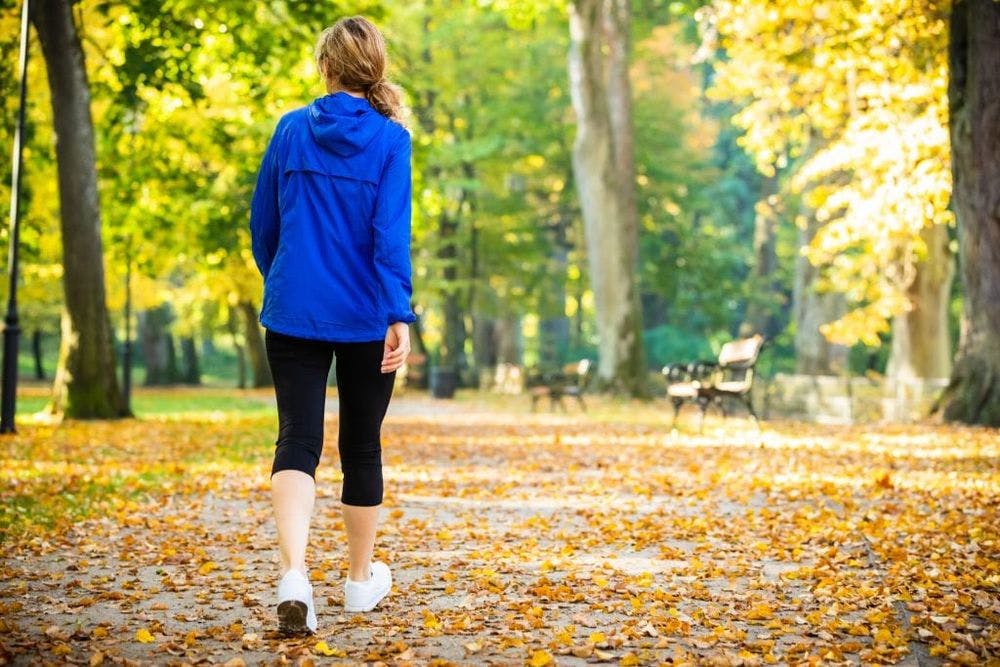 woman walking in park light exercise to calm panic attack in fall