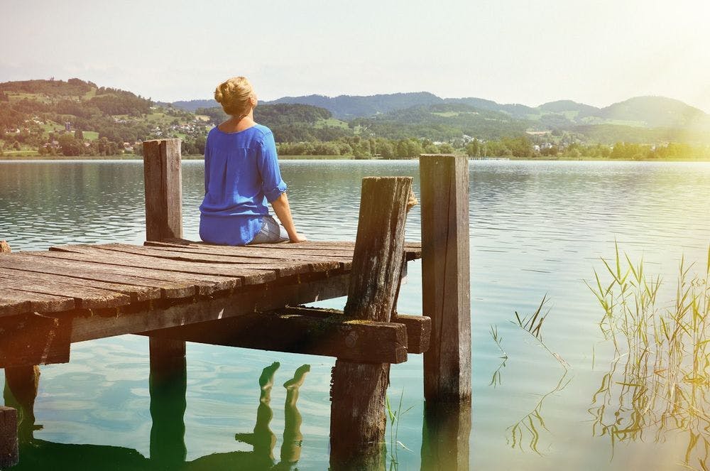 A woman sitting on a dock, enjoying the sun and nature