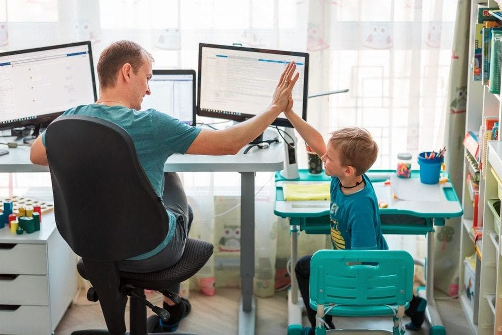 Father with kid working from home, kid has his own space
