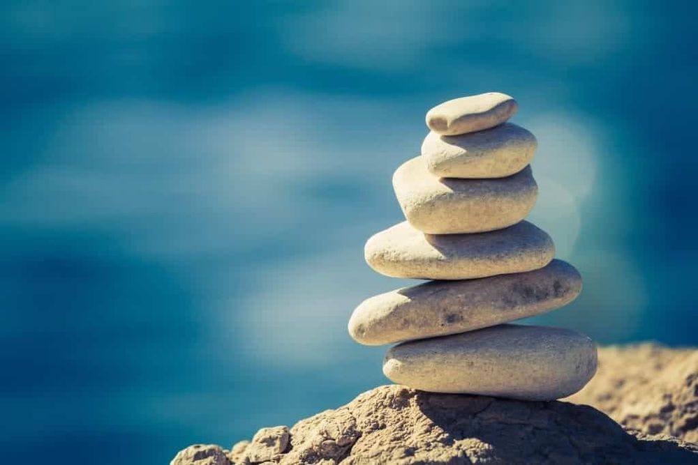 Balance and wellness retro spa concept, inspiration, zen-like and well being tranquil composition. Close-up of white pebbles stack over blue sea