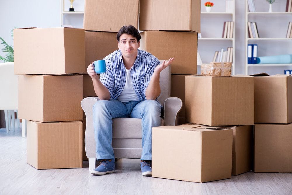 A man looking puzzled and stressed sitting among moving boxes