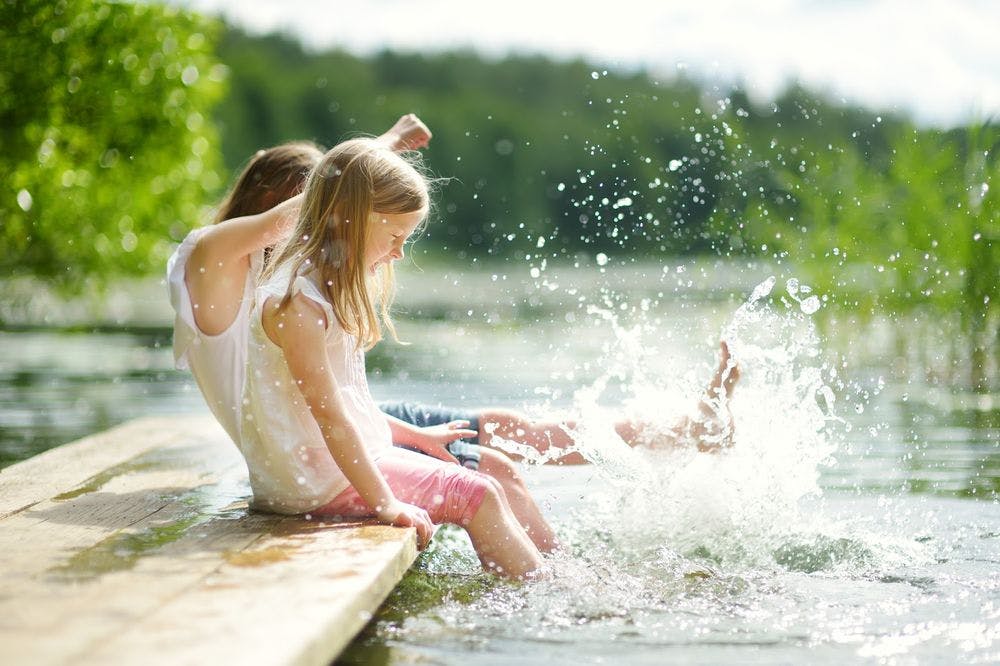 Young girls splashing in the water on a lake dock