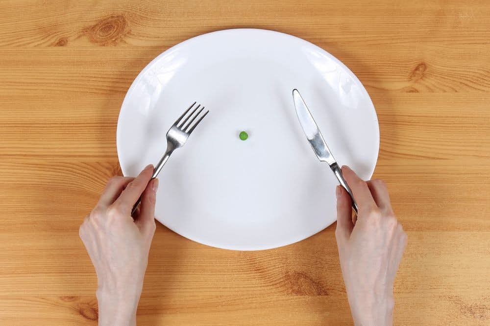 A large plate with a single pea on it 