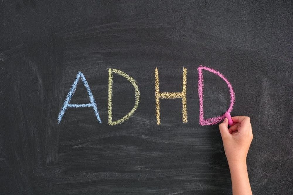 ADHD. Child writing Abbreviation ADHD on a blackboard. ADHD is Attention deficit hyperactivity disorder.