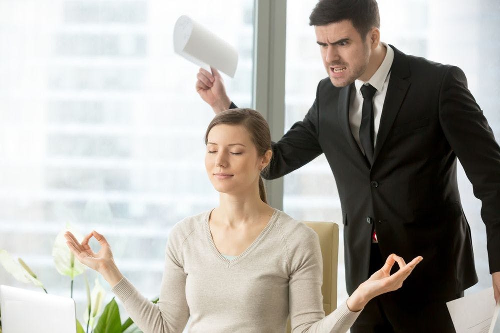 An angry man standing over a woman meditating