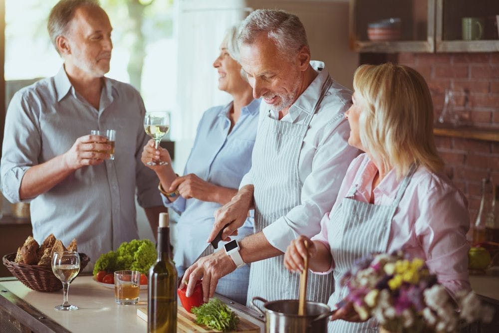 Group of older people cooking, drinking wine, enjoying life, socializing