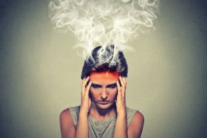 Portrait young stressed woman thinking too hard steam coming out up of head isolated on grey wall background. Face expression emotion perception. Burnout concept